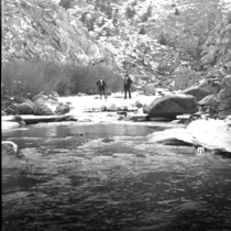 Two men standing next to a creek
